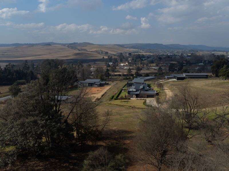 An aerial view of a residential estate featuring multiple modern homes set within a rural landscape with rolling hills and open fields.