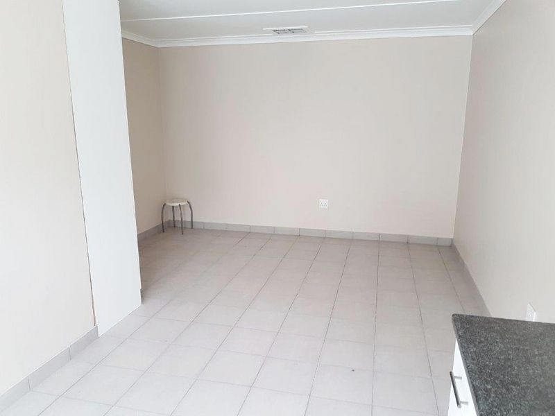 A bright, empty open-plan living area featuring neutral walls and tiled flooring, offering a versatile space ready for custom interior design.