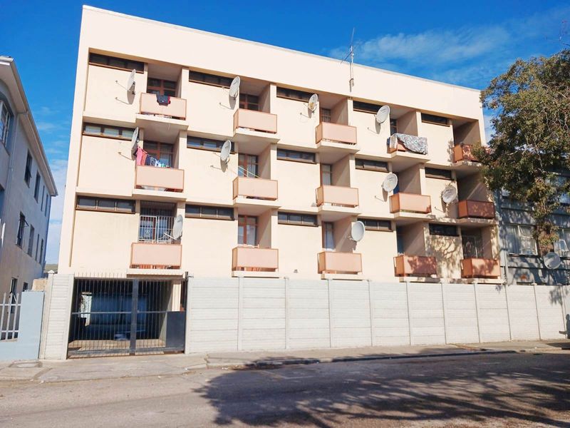 Front elevation of a multi-story apartment building featuring private balconies, a secure gated entrance, and a precast concrete boundary wall.