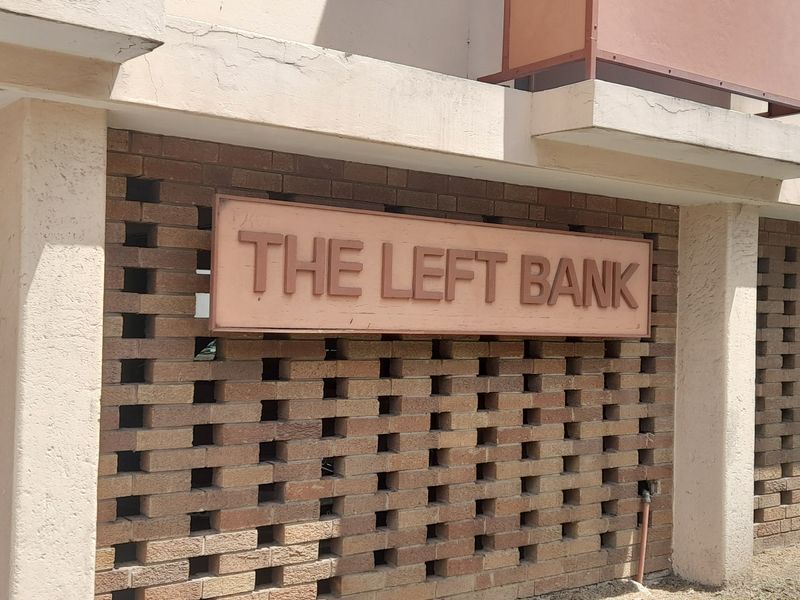 Exterior view of The Left Bank apartment building entrance, featuring a decorative brick screen wall and concrete balcony structures.