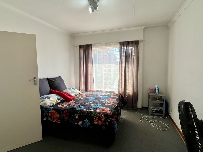 A standard bedroom featuring neutral walls, carpeted flooring, and a window with installed curtain rods.
