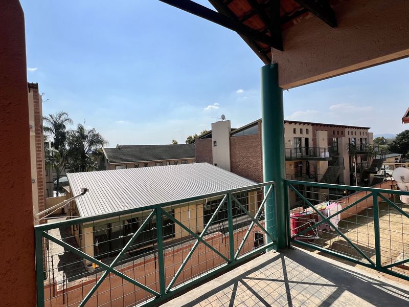 A covered balcony area with metal balustrades, overlooking the surrounding apartment complex and neighborhood.