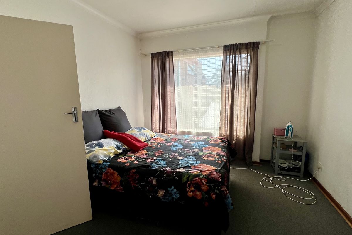 A standard bedroom featuring carpeted flooring and a window with installed curtain rails, providing a functional space for rest.