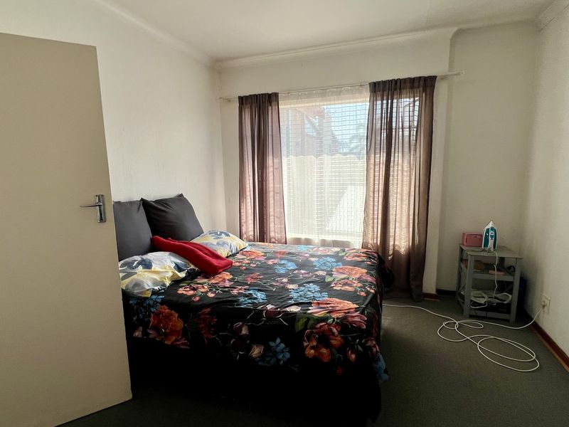 A standard bedroom featuring carpeted flooring and a window with installed curtain rails, providing a functional space for rest.