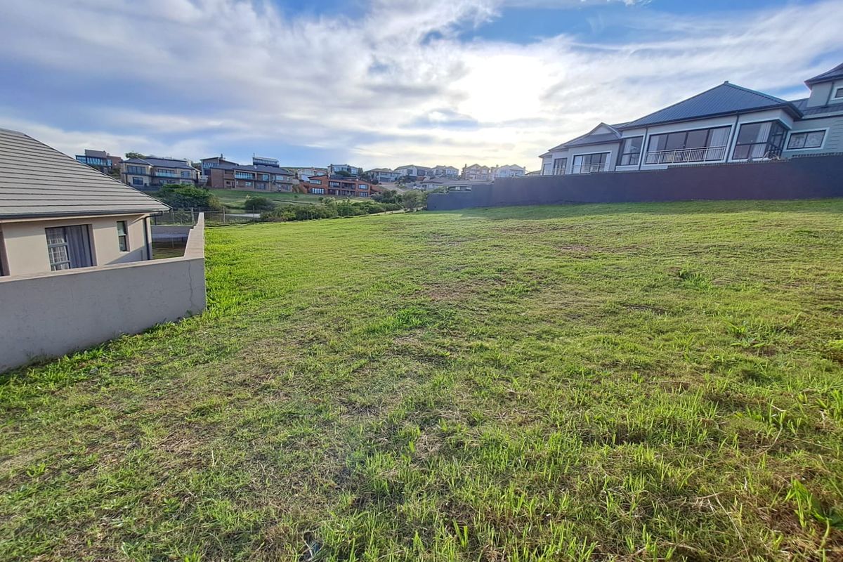 A spacious, level vacant residential plot featuring established grass cover and boundary walls, situated within a developed suburban estate.