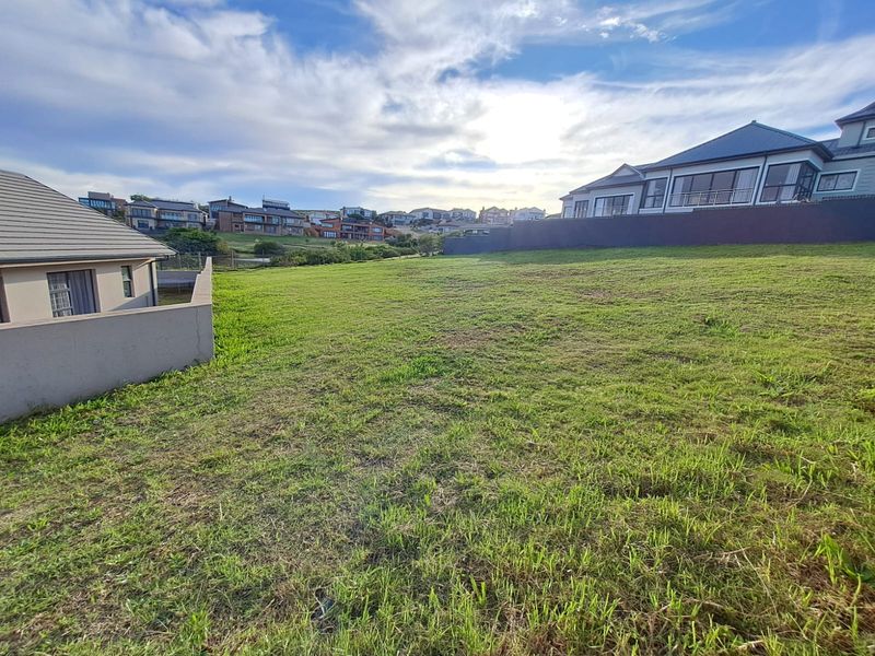 A spacious, level vacant residential plot featuring established grass cover and boundary walls, situated within a developed suburban estate.