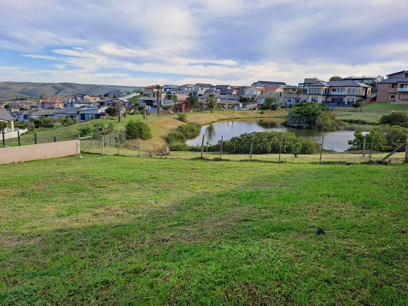 A scenic view overlooking a residential estate pond and surrounding neighborhood landscape from the vacant residential land.
