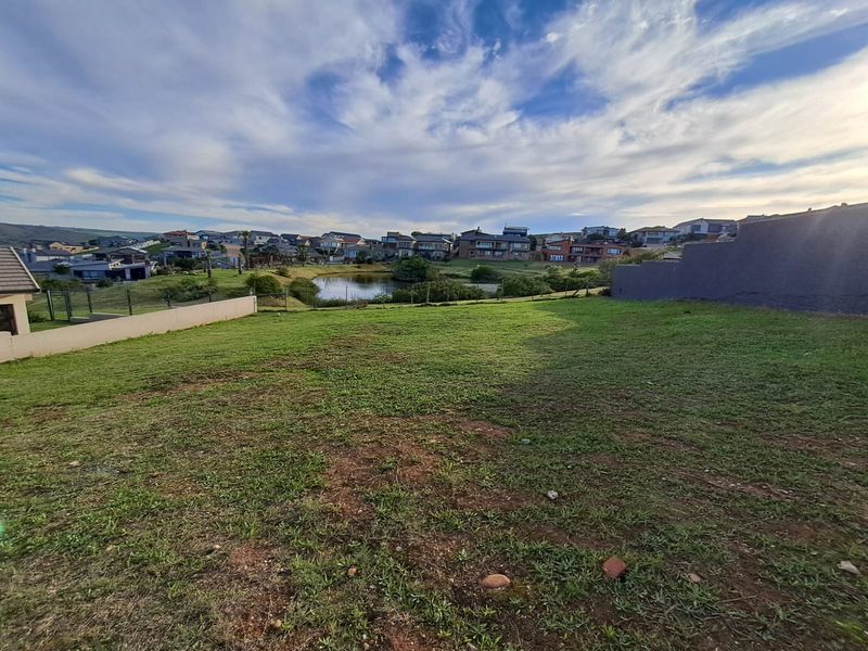 A view of the vacant residential plot overlooking a small pond and the surrounding neighborhood landscape.