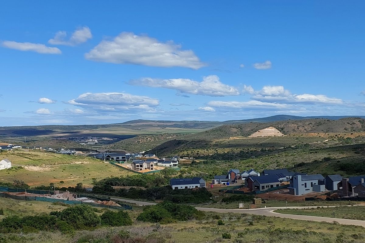 An elevated aerial view of a residential estate development featuring modern homes set within a scenic, hilly landscape.