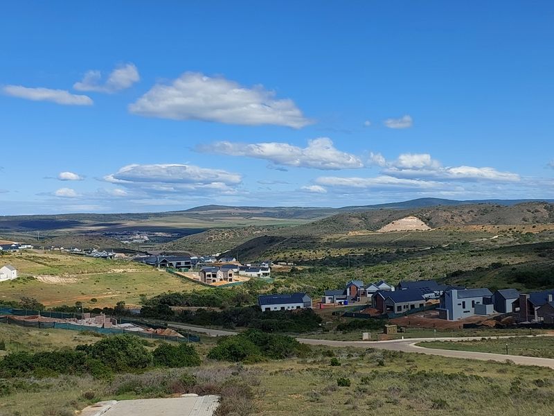 An elevated aerial view of a residential estate development featuring modern homes set within a scenic, hilly landscape.