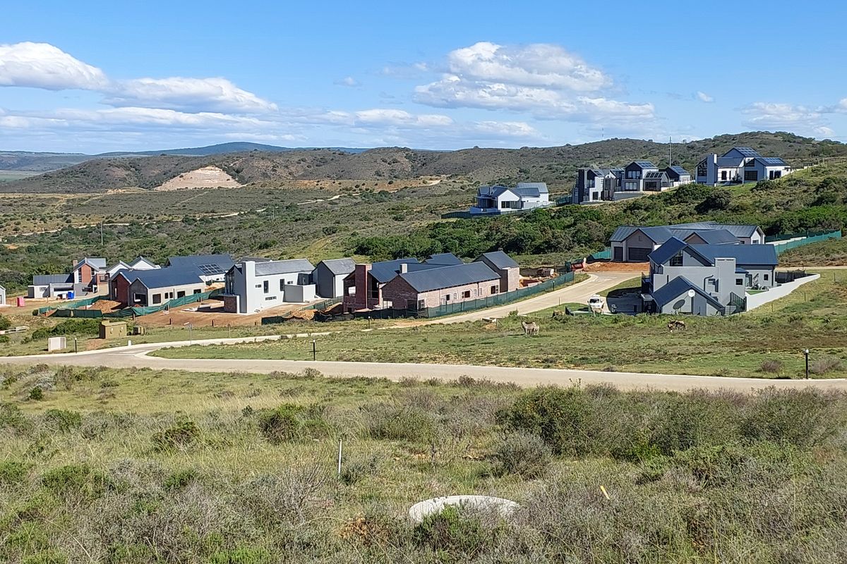 An elevated view of a residential estate featuring modern homes set within a natural landscape and paved road infrastructure.