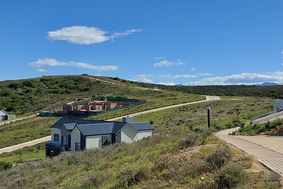 An elevated view of a residential property under development, featuring a modern home with a pitched roof set within a scenic landscape.