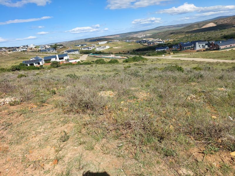 A wide-angle view of the vacant residential land, showcasing the natural sloped terrain and surrounding estate landscape.