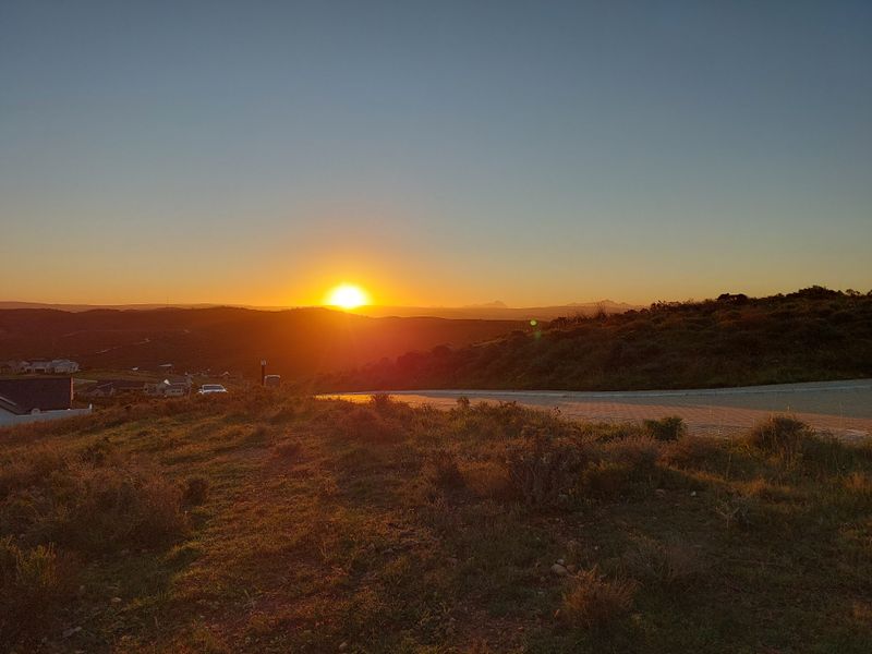 A scenic sunset view overlooking the surrounding landscape and residential area from the vacant land plot.