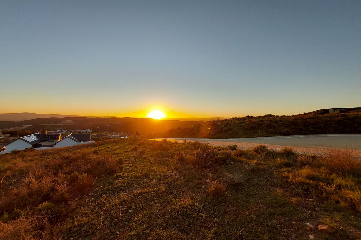 A scenic sunset view overlooking the surrounding landscape and residential area from the vacant residential plot.