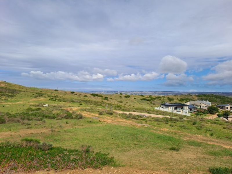 A wide-angle view of the vacant residential land, showcasing the natural coastal landscape and surrounding neighborhood development.