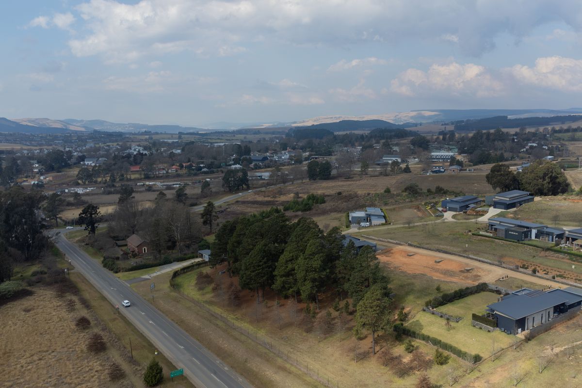 An aerial view of the residential land parcel, showcasing the surrounding landscape, established trees, and proximity to the main road.