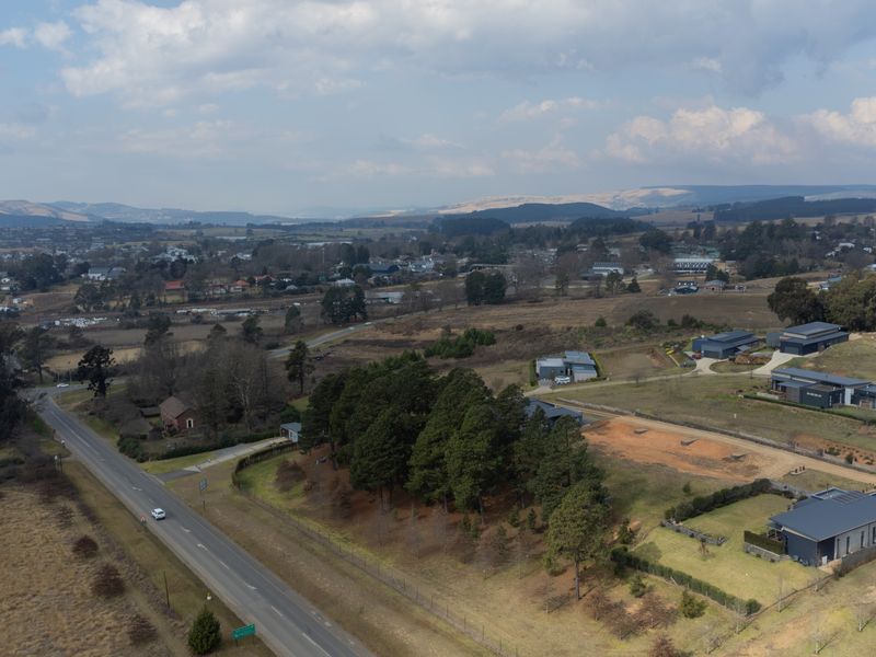 An aerial view of the residential land parcel, showcasing the surrounding landscape, established trees, and proximity to the main road.