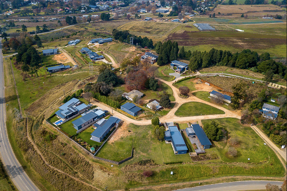An aerial view of a residential estate featuring multiple modern homes, landscaped grounds, and surrounding rural landscape.