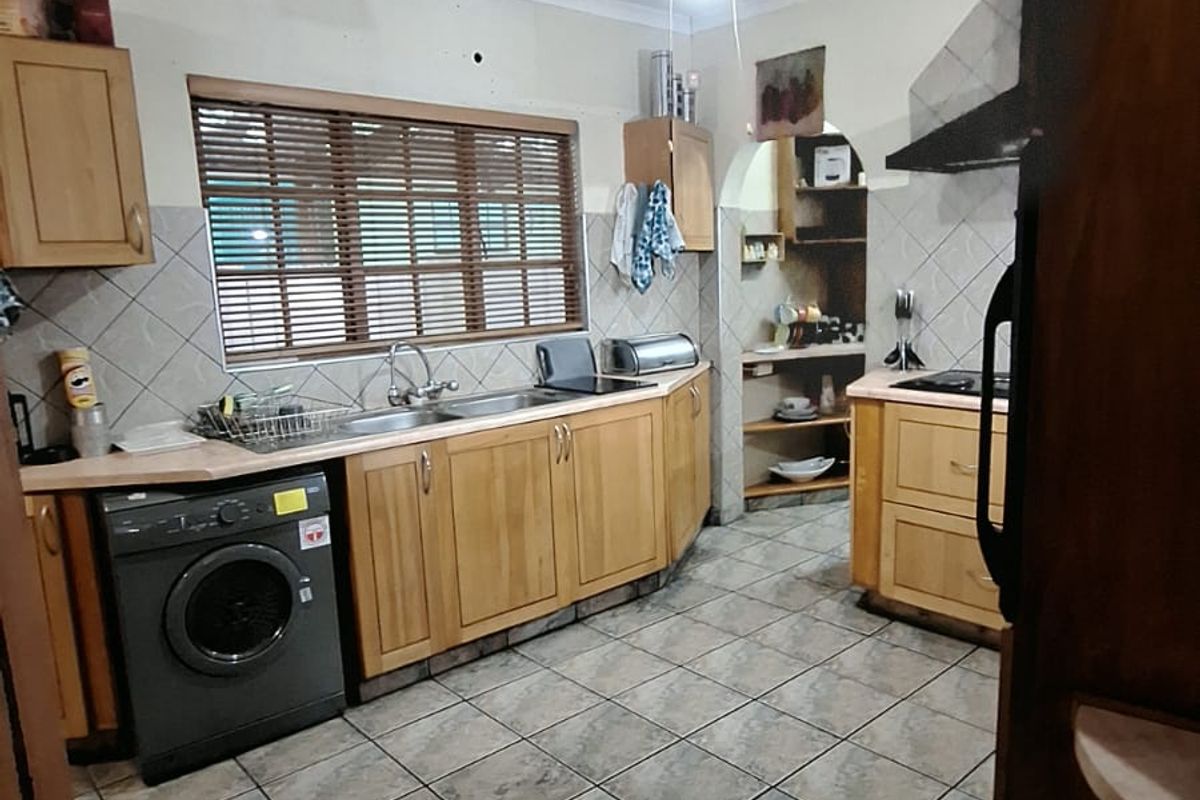 A dated kitchen featuring wooden cabinetry, tiled flooring, and a separate scullery area, requiring cosmetic updates and ceiling repairs.