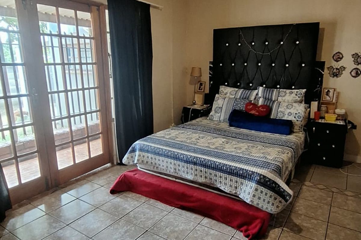 A bedroom featuring tiled flooring, a ceiling fan, and double glass panel doors providing direct access to the outdoor area.