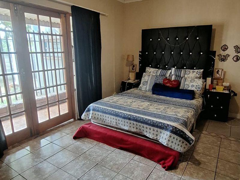 A bedroom featuring tiled flooring, a ceiling fan, and double glass panel doors providing direct access to the outdoor area.