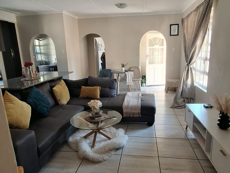 Open-plan living area featuring tiled flooring, archway transitions to adjacent rooms, and a kitchen breakfast bar, creating a functional and connected living space.