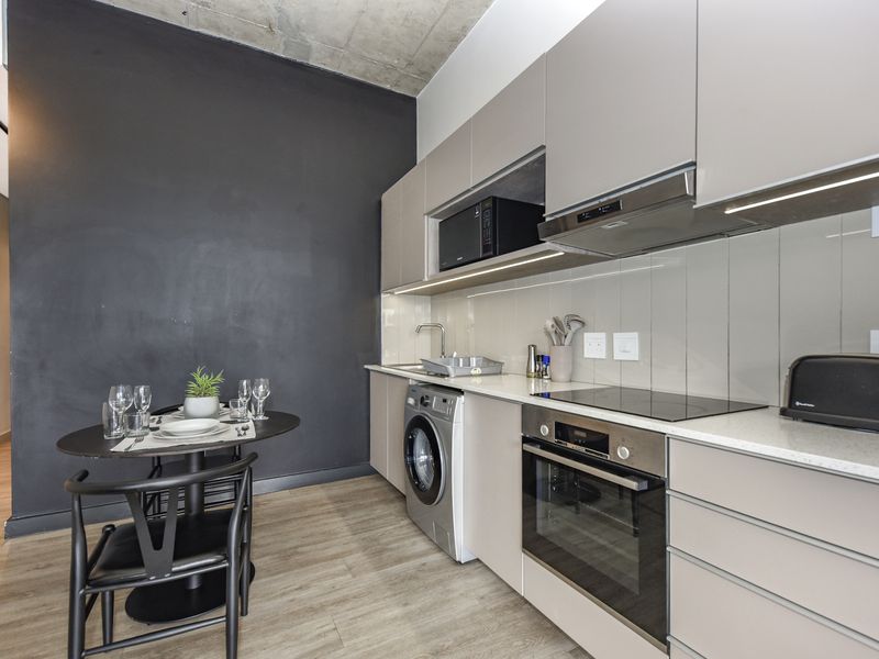 Modern kitchen featuring sleek cabinetry, stone countertops, integrated appliances, and an exposed concrete ceiling, creating a contemporary and functional culinary space.