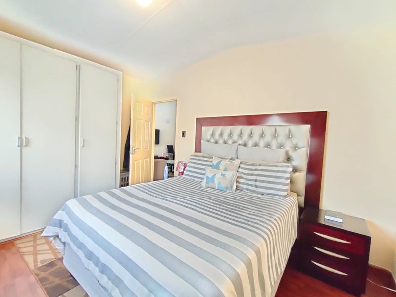 A bedroom featuring built-in cupboards and laminate flooring, offering a functional space with neutral wall finishes.