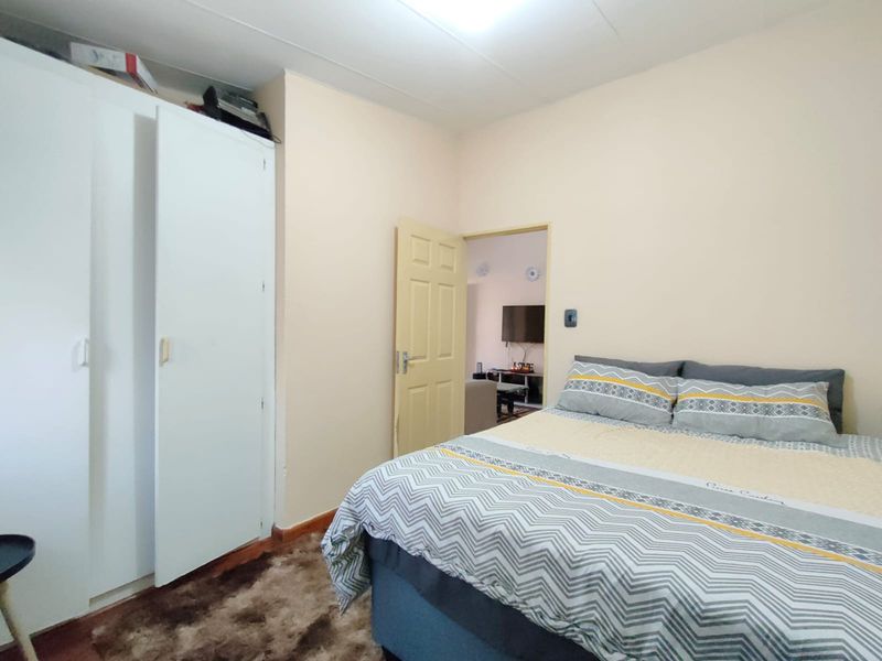 A functional bedroom featuring a built-in wardrobe and neutral wall finishes, offering a comfortable space with direct access to the living area.
