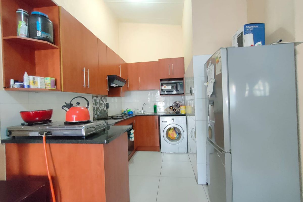 A functional kitchen featuring wood-finish cabinetry, granite countertops, tiled backsplash, and integrated appliance spaces, providing a practical layout for daily meal preparation.