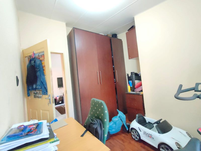 A bedroom featuring laminate flooring and a built-in wardrobe, providing functional storage space within the room.