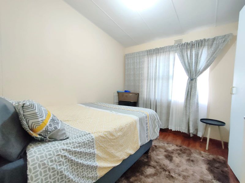 A functional bedroom featuring laminate flooring and a ceiling vent, offering a neutral canvas for personalization.