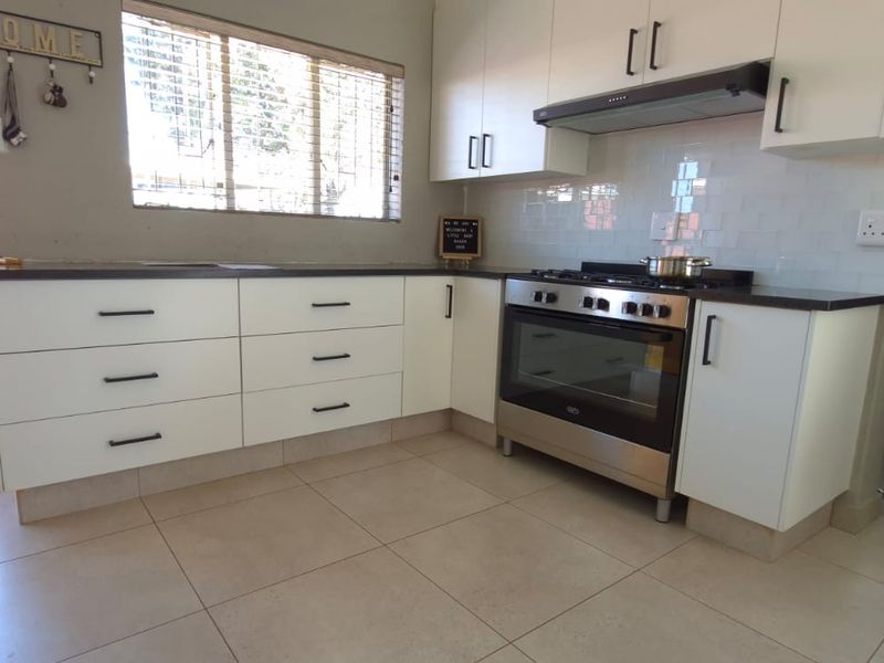 Modern kitchen featuring white cabinetry, a gas stove with extractor fan, subway tile backsplash, and neutral tiled flooring.
