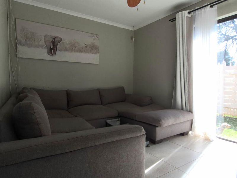 A living room featuring tiled flooring and a large sliding glass door providing natural light and access to the outdoor area.