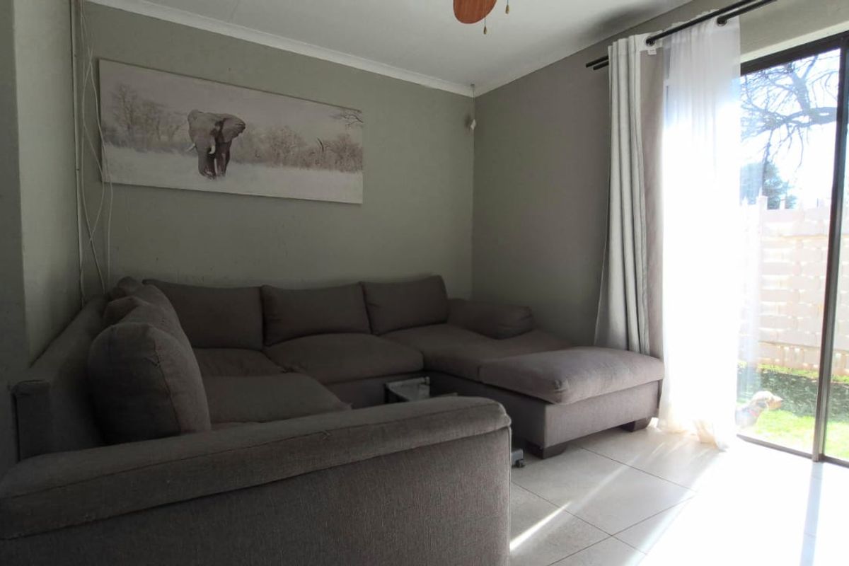 A living room featuring tiled flooring and a large sliding glass door providing natural light and access to the outdoor area.