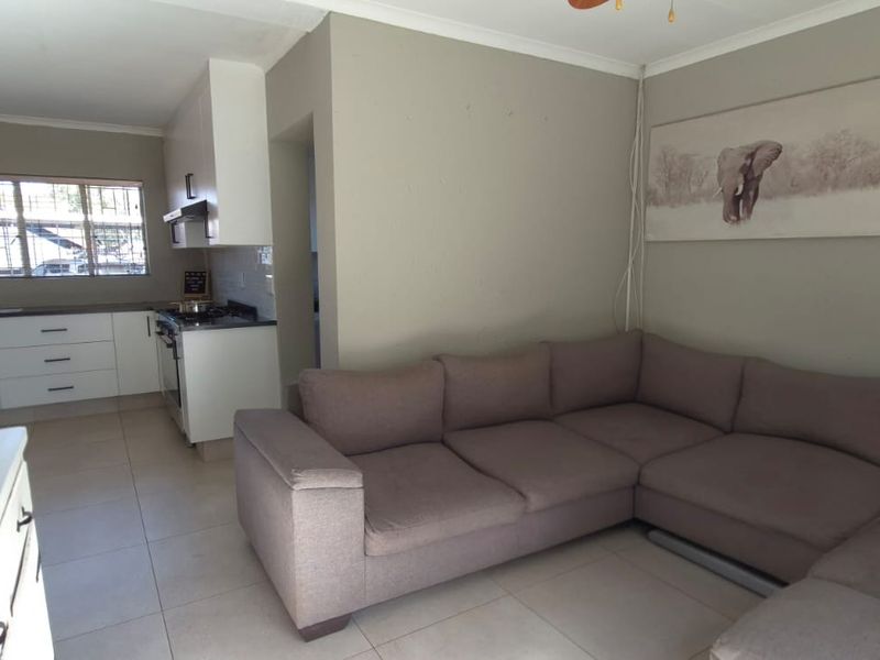 Open-plan living area featuring tiled floors and a functional kitchen with built-in cabinetry, gas hob, and extractor fan.