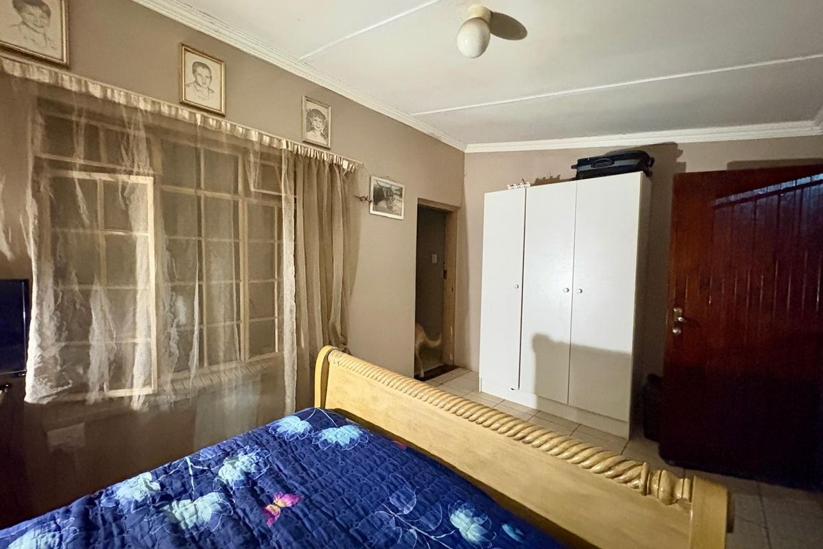 A bedroom featuring tiled flooring, a built-in wardrobe, and a timber door, requiring cosmetic updates to improve its overall condition and appeal.