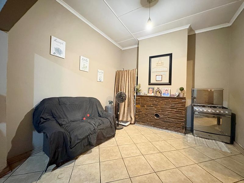 Living area featuring tiled flooring, a stone-clad fireplace feature, and a freestanding gas stove, offering a functional space with potential for cosmetic updates.