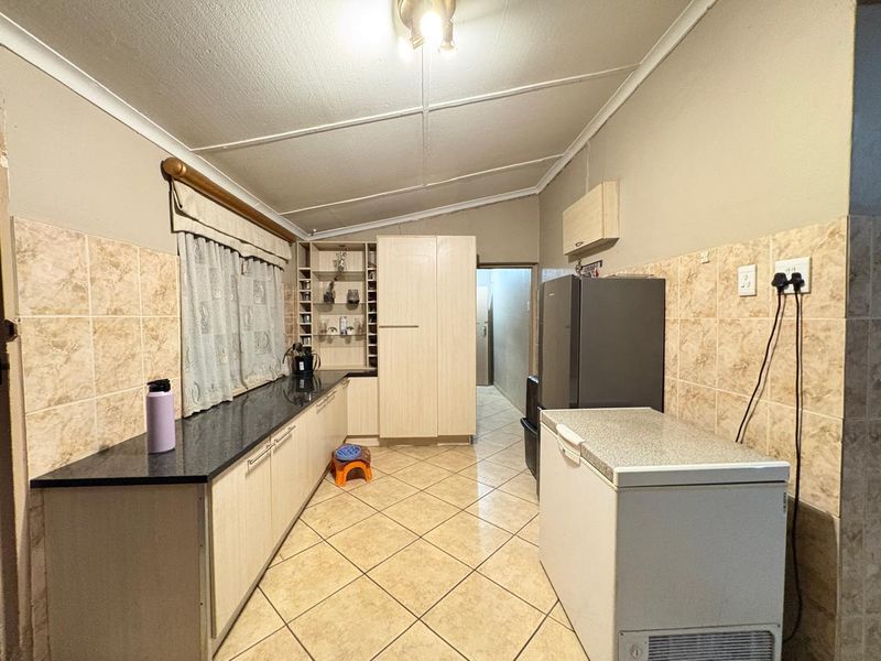 A functional kitchen featuring laminate cabinetry, granite countertops, tiled backsplash, and tiled flooring, offering a practical layout for daily meal preparation.