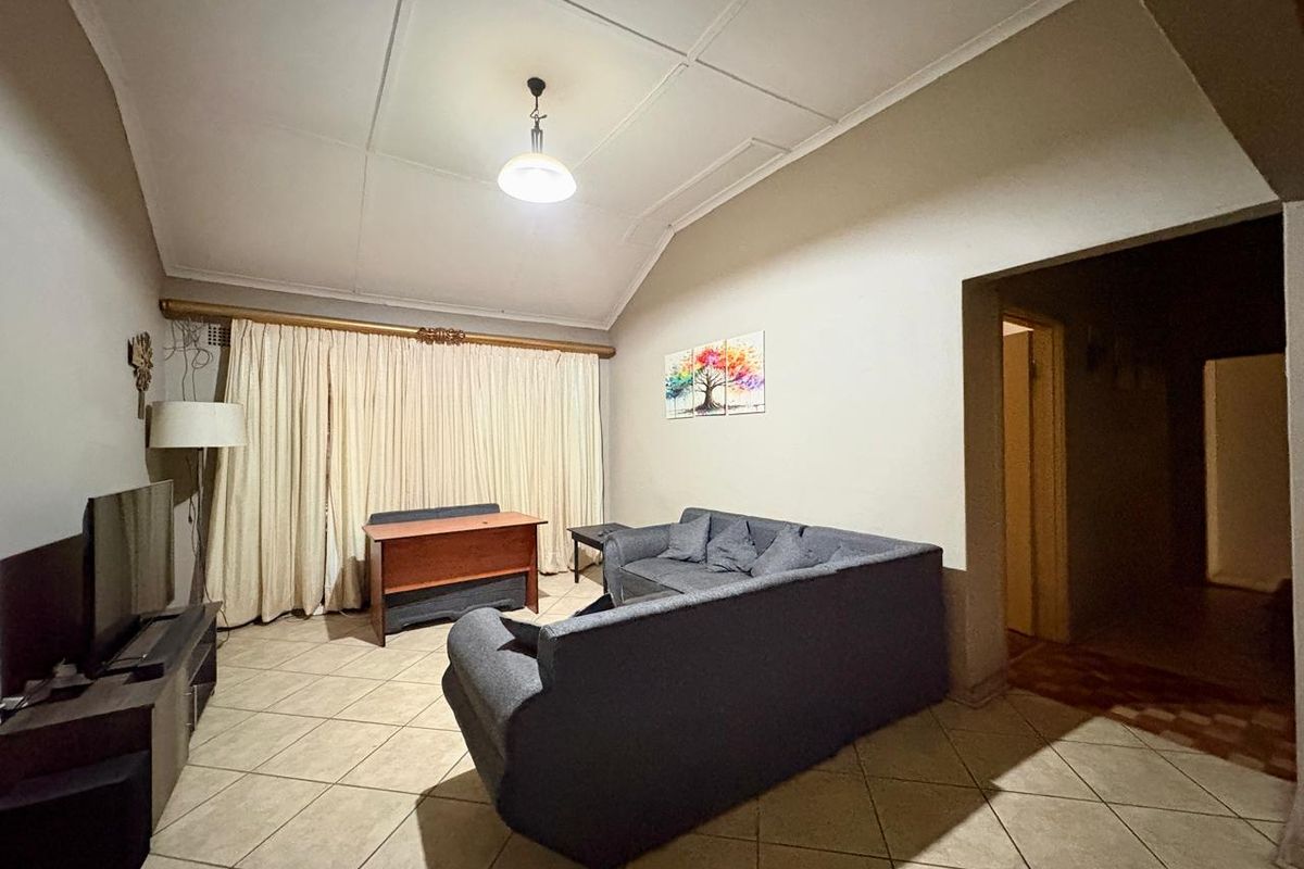 A living room featuring tiled flooring and a vaulted ceiling, providing a spacious area for relaxation and entertainment.