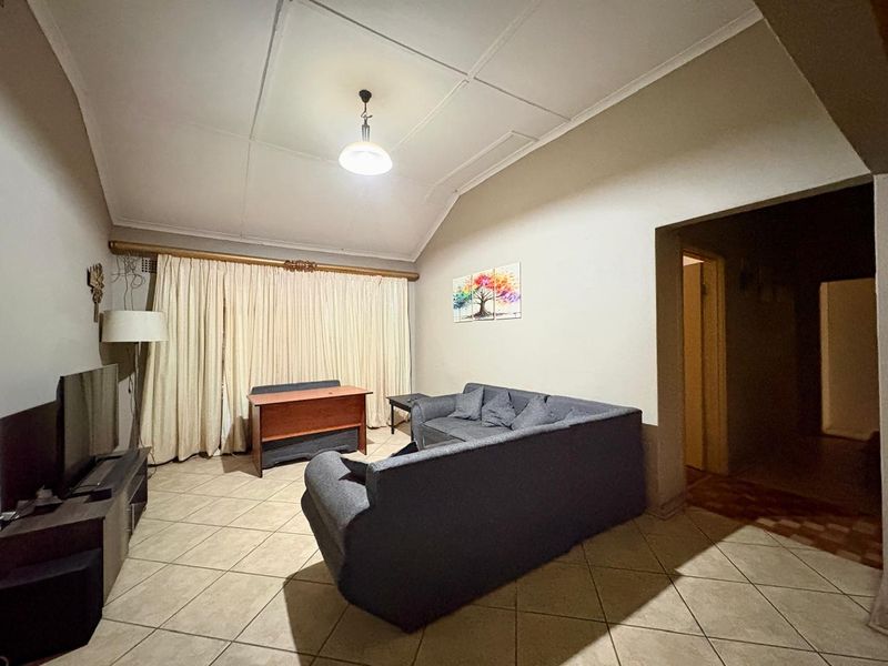A living room featuring tiled flooring and a vaulted ceiling, providing a spacious area for relaxation and entertainment.