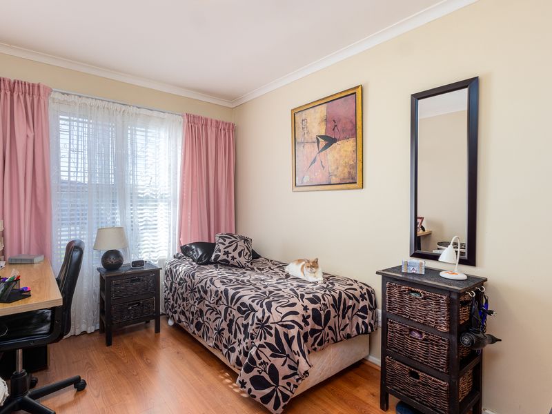 A functional bedroom featuring laminate flooring and neutral wall tones, offering a comfortable space with natural light through the window.