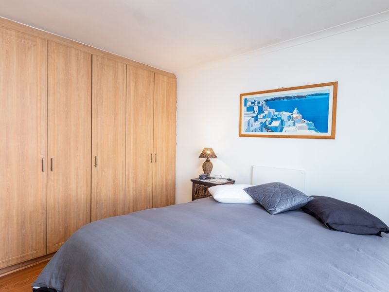 A well-maintained bedroom featuring light wood-toned built-in wardrobes and laminate flooring, offering a clean and functional living space.