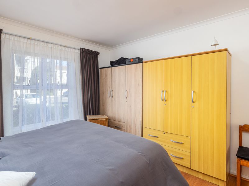 A bedroom featuring laminate flooring, coving, and built-in wardrobe storage units.
