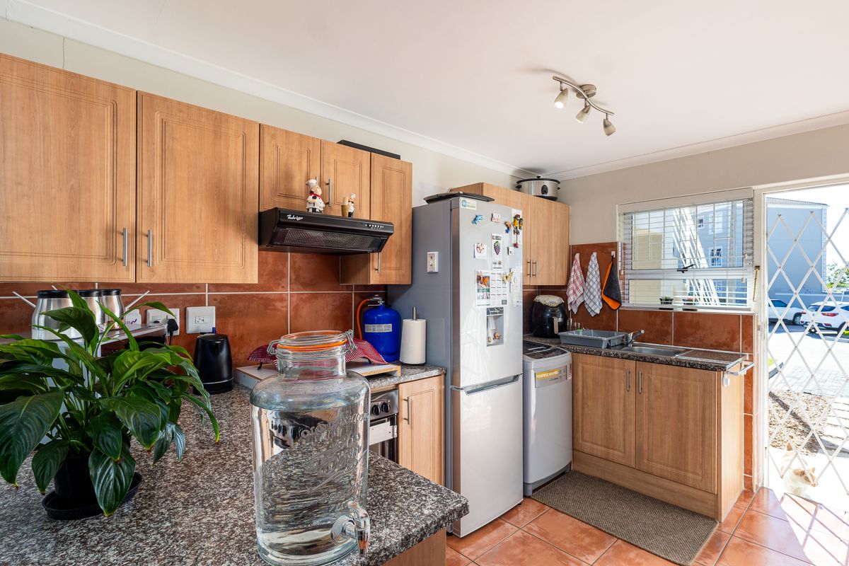 Functional kitchen featuring laminate cabinetry, granite countertops, tiled backsplash, and direct access to an outdoor area through a security gate.