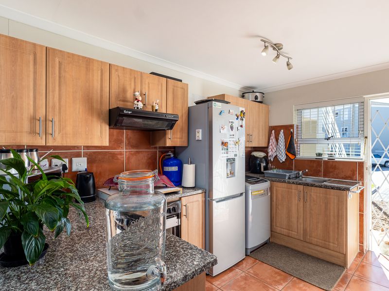 Functional kitchen featuring laminate cabinetry, granite countertops, tiled backsplash, and direct access to an outdoor area through a security gate.