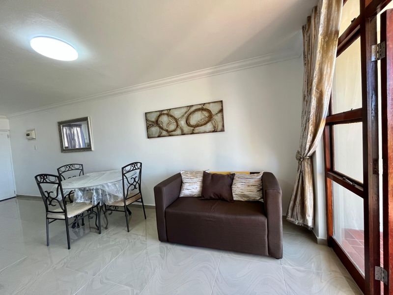 A bright living area featuring polished tiled flooring, coved ceiling cornices, and a timber-framed glass door providing access to the outdoor space.