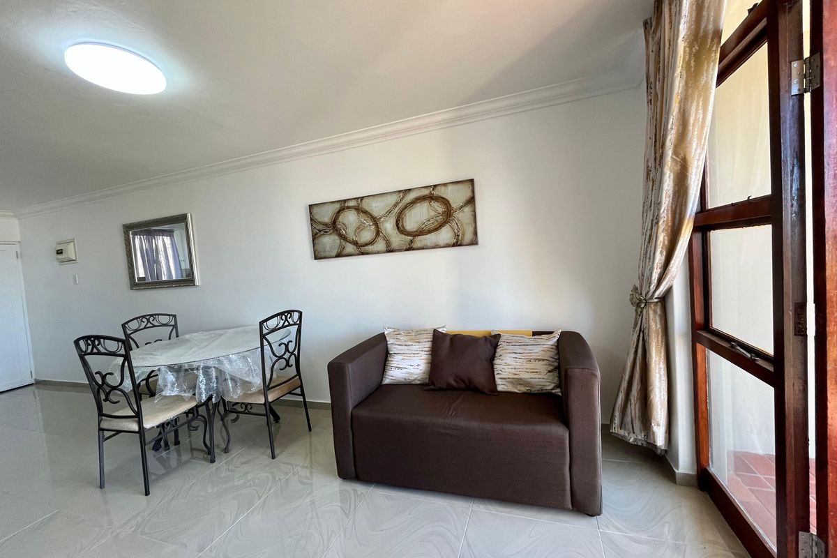 A bright living area featuring polished tiled flooring, coved ceiling cornices, and a timber-framed glass door providing access to the outdoor space.