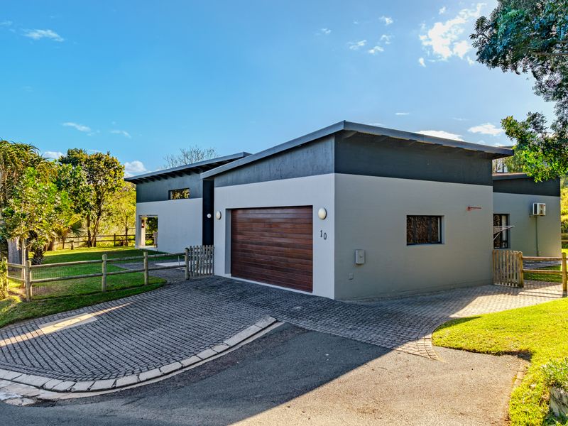 Modern single-story residence featuring a paved driveway, integrated garage with timber door, and well-maintained surrounding garden area.